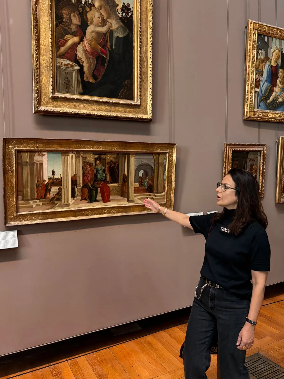 Orlie reading Renaissance biblical scenes with visitors at the Louvre